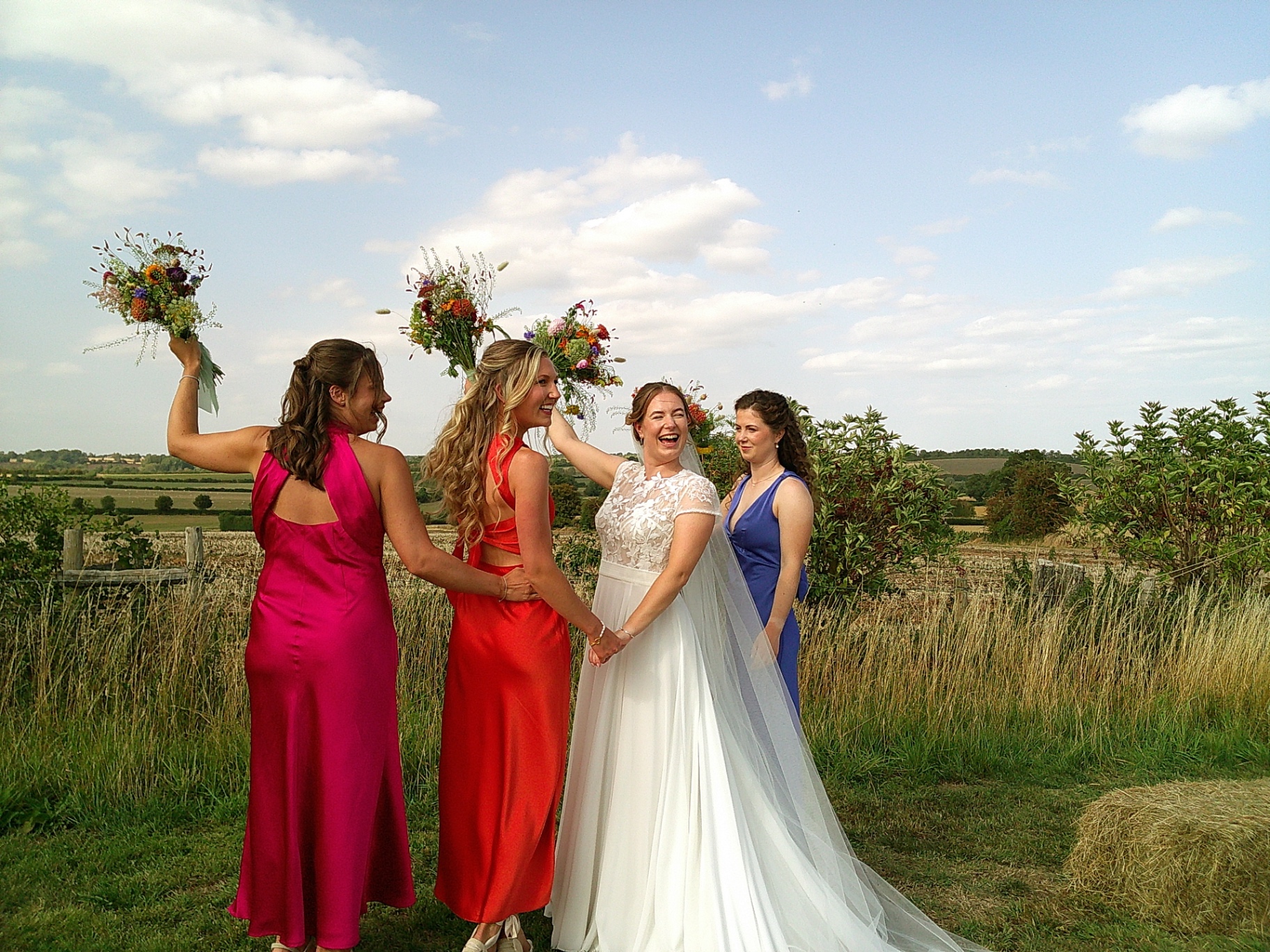 Bride laughing with her bridesmaids in a sunny field, shot on SnapBox